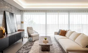 A modern living room featuring a marble coffee table, white fabric sofa, and glass sconce.