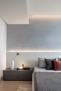 A minimalist bedroom featuring a bed with a gray concrete headboard and geometric patterned bedding, accompanied by a sleek n