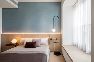 A modern minimalist bedroom with wooden furniture and a glass lamp on the side table.
