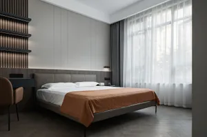 A contemporary minimalist bedroom with a bed dressed in brown blankets and a white bedspread, featuring woven curtains, woode