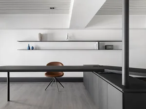 Modern minimalist home office with black wooden desk and floating shelves.