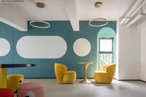 A modern office lounge area with yellow upholstered furniture and a fabric-covered partition.