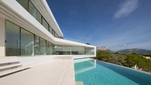A modern residential exterior featuring glass walls and concrete elements.
