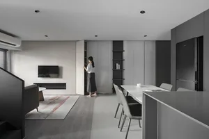 A modern residential kitchen with a minimalist design, featuring a white countertop and black appliances.