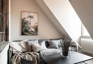 Modern minimalist living room featuring a gray couch adorned with neutral-colored pillows and a furry blanket, complemented b