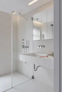 Modern minimalist bathroom with glass shower enclosure, white porcelain fixtures, and sleek design.