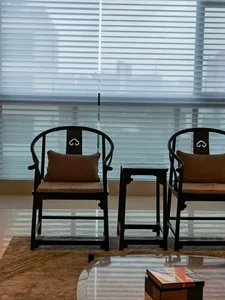 A modern interior space with black furniture and floor cushions, featuring a glass coffee table and a small wooden table.