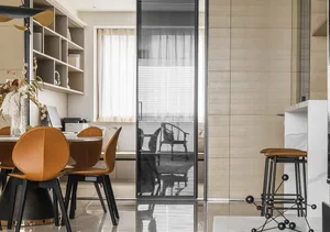 A modern living and dining room with beige tiled walls, wooden furniture, and glass doors.