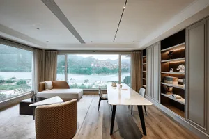 A modern living room with marble accents and a leather sofa, featuring a large window overlooking a scenic landscape.