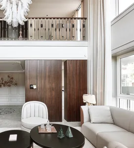 A modern living room featuring white furniture, dark wood panels, and elegant lighting fixtures.