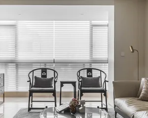 A modern living room featuring neutral-colored furniture and decor, with a glass coffee table, leather sofa, and two armchair