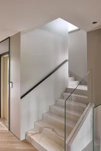 Modern staircase with white marble steps, glass railing, and chrome handrails.