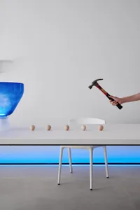 A minimalist home decor setup featuring plastic spheres and a hammer on a white table.