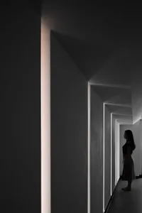 A minimalist interior space featuring concrete walls and illuminated light strips.