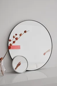 A minimalist interior design with a large circular mirror made of glass.