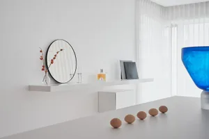 A minimalist white space with a glass vase, five eggs, and decorative elements.