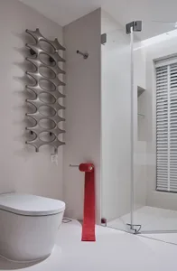 Modern bathroom featuring a white tub, toilet, and sink with glass shower enclosure and red toilet paper