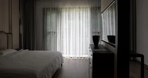 A modern bedroom with a bed, curtains, and a window.