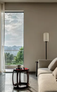 Modern living room featuring textured cushions, a marble side table, and a large window with a view of mountains and blue sky