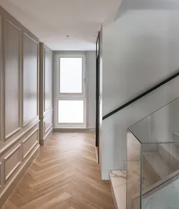 A modern staircase hallway featuring wooden flooring and glass railings.
