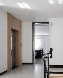 A modern entrance hall featuring wooden panels, white walls, and a door leading to another room.
