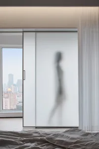A modern minimalist residential space featuring glass walls and a view of the cityscape.