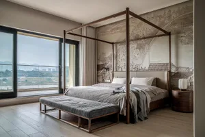 A minimalist bedroom with a wooden frame bed and a large window overlooking a scenic landscape.
