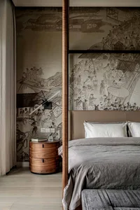 A modern bedroom featuring a four-poster bed with a brown headboard, gray bedding, and a wooden bedside table with a lamp and