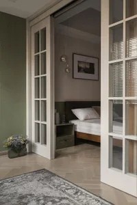 Modern bedroom with a white bed frame, green walls, and a wooden floor.