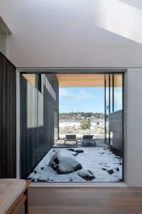 Modern residential interior with glass walls, wood accents, and stone elements.