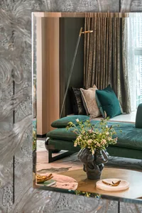 Modern living room featuring a green velvet couch, marble coffee table, and decorative mirror.