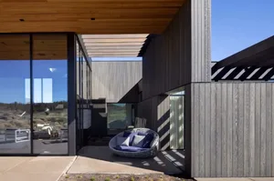 A modern residential exterior featuring a wooden structure with large glass windows.