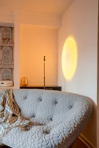 A cozy modern living room with a textured blue sofa and decorative lamp casting a warm glow.