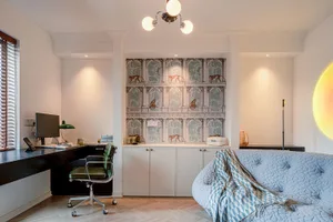 A modern home office space with a desk, computer, and quilted sofa.