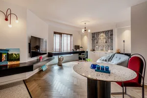 Modern living room with a terrazzo floor, a red accent chair, and a television mounted on the wall.