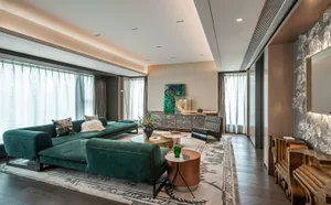 Modern living room featuring a green velvet sectional sofa, marble coffee table, and wooden side tables.