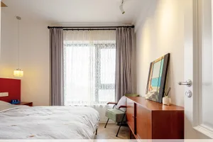 A minimalist bedroom with a bed, chair, and sideboard.