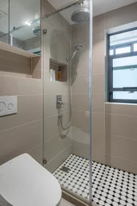 A modern bathroom featuring minimalist design with tiled flooring and a glass-enclosed shower.
