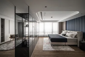 Modern minimalist bedroom with wooden floor, upholstered bed, and glass partition.