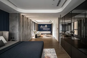 Modern bedroom with concrete walls, wooden flooring, and a blue accent wall.