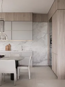 Modern minimalist kitchen featuring marble finishes, white cabinets, and a round dining table with chairs.