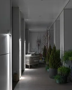 A minimalist interior patio with a wooden deck, white furniture, and potted plants.