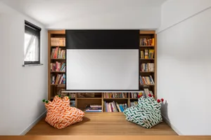 A modern industrial home theater and library with a large screen and a variety of books.
