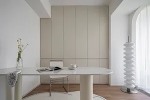 Minimalist home office space featuring a white desk, chair, and cabinet.