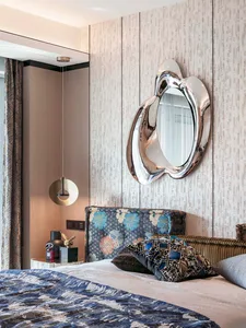 A modern bedroom with a metallic texture headboard, decorative pillows, and a window with curtains.