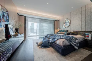 Modern bedroom with minimalist design and patterned fabric, featuring a bed with blue and white bedding, a dresser, and a lar