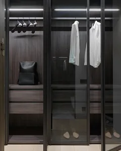 Modern dark wood metallic closet with glass doors, hanging clothes, and shoe rack.