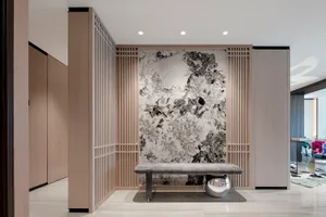 Modern entrance hall featuring a marble wall and bench.