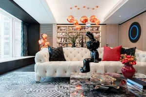 Modern living room featuring a white sofa adorned with red and black decorative elements.