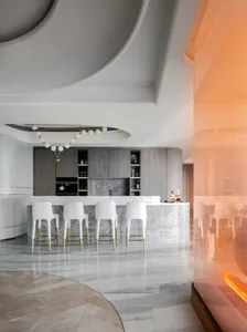 Modern kitchen featuring marble countertops and flooring, with white chairs and a minimalist design.
